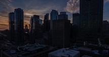 Sunset cityscape with silhouetted skyscrapers against a dramatic sky, Aerial view