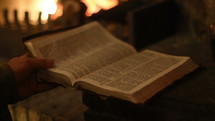 man reading a Bible fireside 