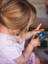 a little girl toddler plays with some colored toys