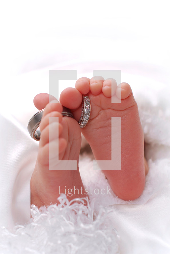 infant's feet with wedding bands around the toes