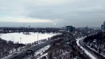 Aerial shot of Don Valley Parkway and Riverdale Park East. Cityscape view of Toronto on a winter day. Drone moving forward while approaching to a group of people sliding on the snow. Moderate traffic.