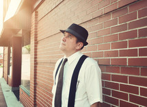 a man in a hat and suspenders looking up to God 