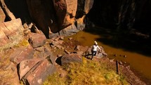 Aerial of a woman hiking and exploring a small canyon