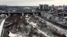 Aerial scene of Prince Edward Viaduct in urban downtown Toronto on a cold winter day. Aircraft is doing an orbit shot right above Don Valley Parkway and Don River. Moderate vehicular traffic. 