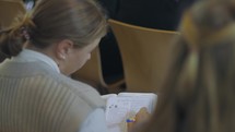 Young woman writing notes and journaling during a Bible teaching