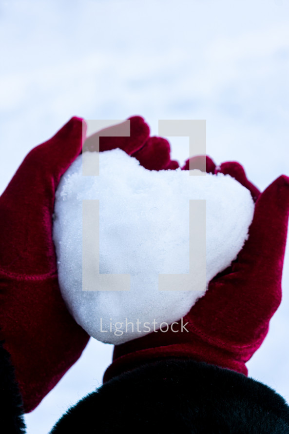 snowball in the shape of a heart in cupped hands 