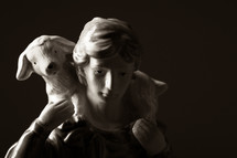 figurine of a shepherd holding a sheep 