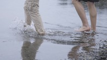 Two men walk into water at the ocean together to be baptized.