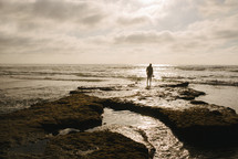 man walking on a rocky beach 