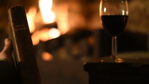 person holding a Bible fireside with a glass of wine 
