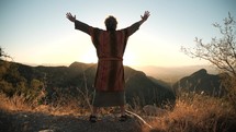 A Bible prophet praising God on a mountain top at sunset