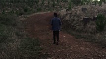 a teen boy walking down a trail alone 