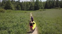 people with kayaks walking on a worn path 