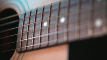 close-up of the strings of a guitar as a man plays