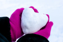 snowball in the shape of a heart in cupped hands 