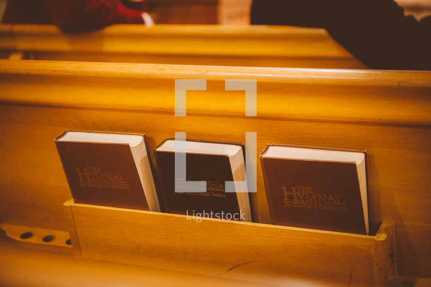 Bible and hymnals on the back of a church pew 