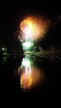 Fireworks over water with boats watch