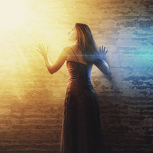 woman looking up at the sun with her hands against a wall 