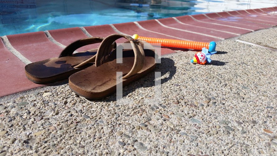 flip flops and dive stick on the edge of a pool 