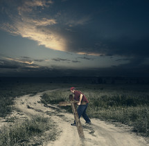 man carrying a cross along a dirt road