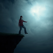 A blindfolded woman walking off the edge of a cliff. 