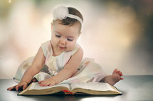 an infant turning the pages of a Bible 