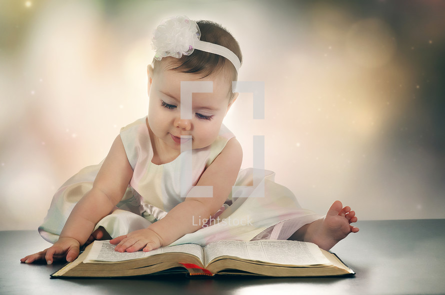 an infant turning the pages of a Bible 
