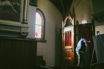 A young man entering a confessional for the sacrament of penance in a Catholic church