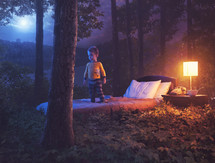 Surreal image of a young boy on his bed in the middle of the night forest.