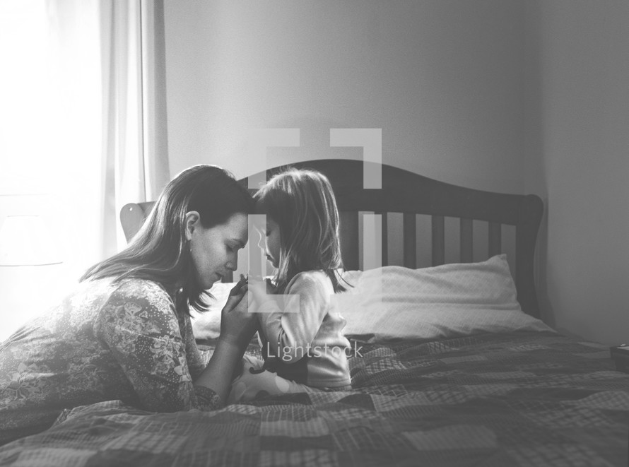 A mother and daughter in prayer at bedtime