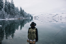 a woman backpacking near a snowy lake shore 
