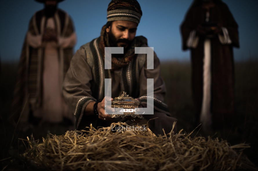 a wiseman presenting a gift to baby Jesus 