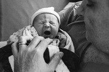 mother holding a yawning newborn 
