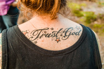 Tattoo on a woman's back - trust in God 