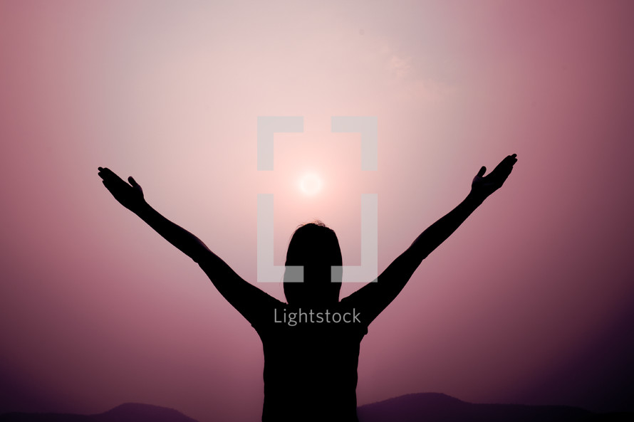 silhouette with raised hands and purple sky 