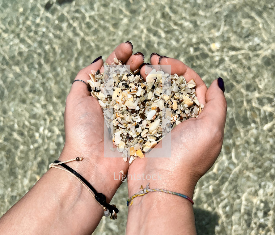 Hands in the shape of a heart with shells from Playa Conchal beach in Costa Rica.