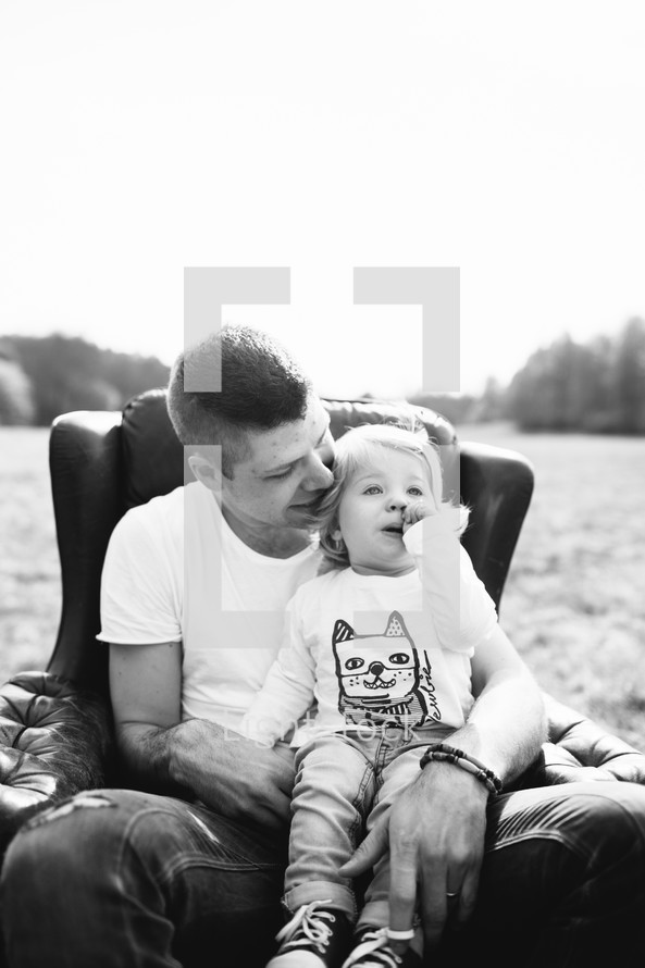 father and daughter sitting in a chair outdoors 