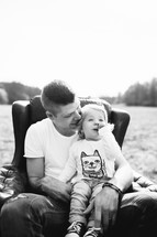 father and daughter sitting in a chair outdoors 