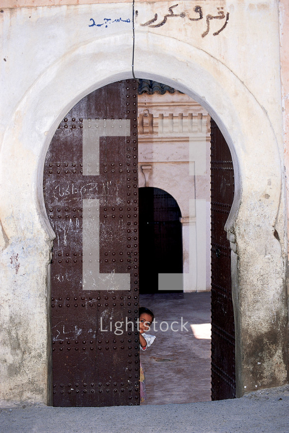 Child peeking through an ornate doorway