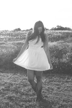 a young woman standing in a dress and cowboy boots 