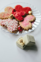 a ring in a box and cookies on a plate 