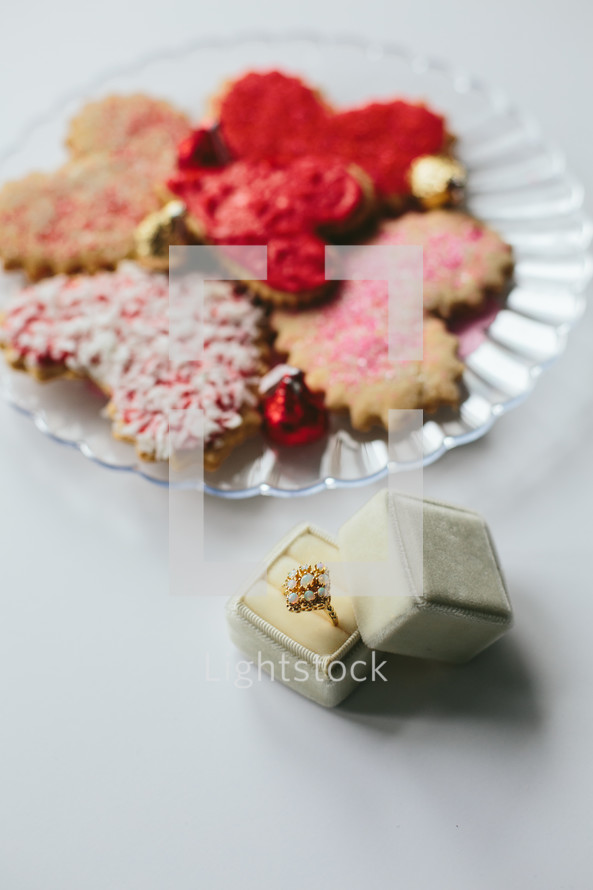 a ring in a box and cookies on a plate 