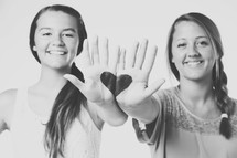 Two girls with heart painted on their hands.