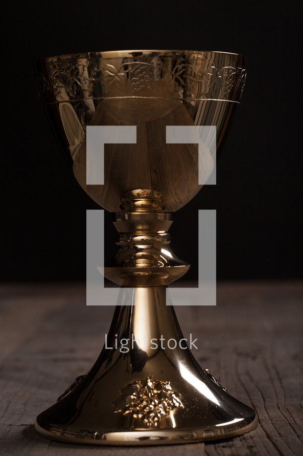 A golden wine goblet on a wooden surface.