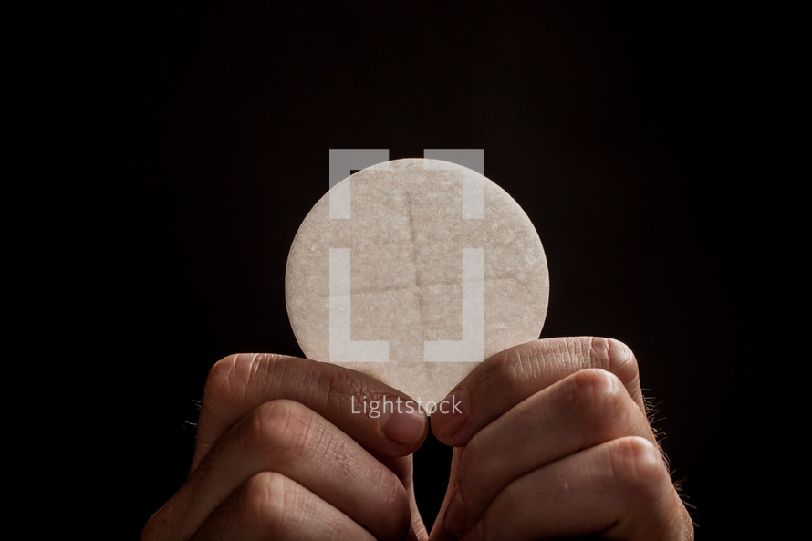 Hands holding a communion wafer.