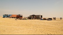People unloading supplies from trucks in the desert.
