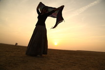 woman dancing with a scarf in the desert 