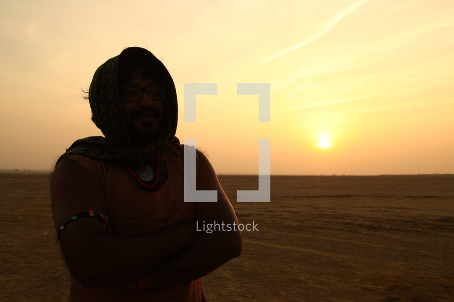 man standing in a desert with a scarf over his head 