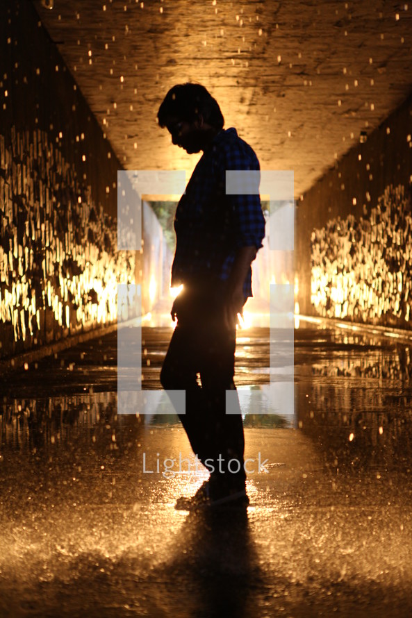 man standing in a glowing wet tunnel 