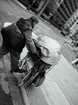 homeless man pushing a shopping cart 